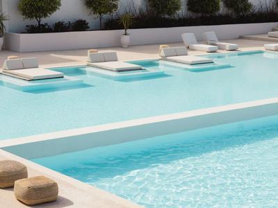 Moderner Hotelpool mit eingebauten Liegen, umgeben von Pflanzen und Sitzkissen.
