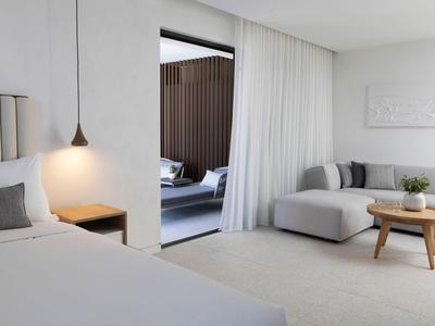 Modernes Hotelzimmer mit hellem Bett, gemütlicher Sitzecke und offenem Blick auf Terrasse.