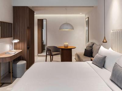 Modern eingerichtetes Hotelzimmer mit großem Bett, Holzmöbeln und warmem Licht.