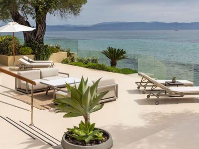 Moderner Hotelpoolbereich mit Liegestühlen und Blick auf das Meer.