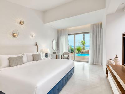 Modernes Schlafzimmer mit großem Bett und Blick auf Pool und Palmen.