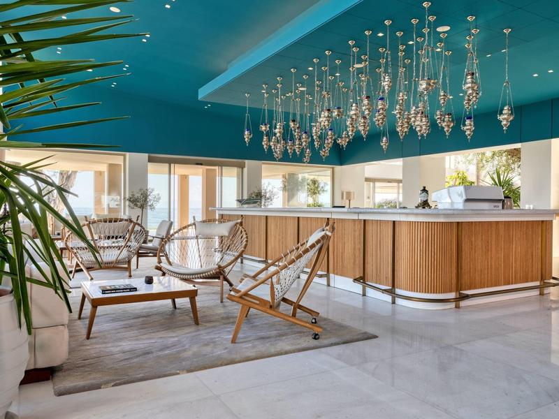 Moderner Empfangsbereich mit Holztheke, blauer Decke und hängender Glasleuchte, gemütliche Sitzgruppe.