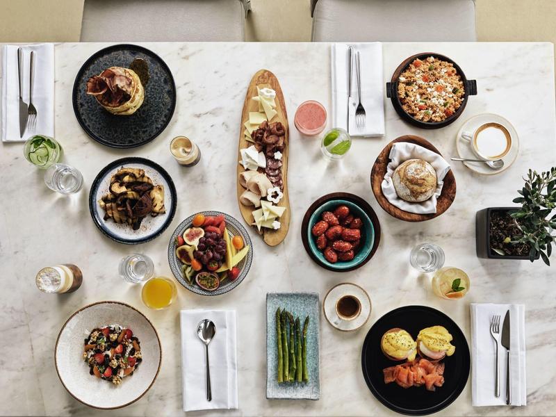 Tisch mit vielfältigen Speisen: Obst, Gemüse, Brot, Eierspeisen, Getränke und Kuchen.