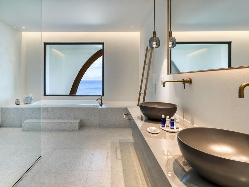 Modernes Badezimmer mit zwei großen schwarzen Becken, großen Spiegeln und heller Marmorfläche.