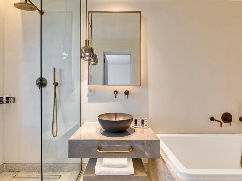 Modernes Badezimmer mit grauer Waschtischplatte, schwarzer Schüssel und ebenerdiger Dusche.