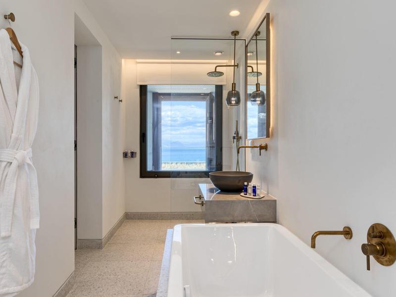 Moderner weißer Wellness-Badezimmer mit freistehender Wanne und Fenster mit Blick auf den Himmel.