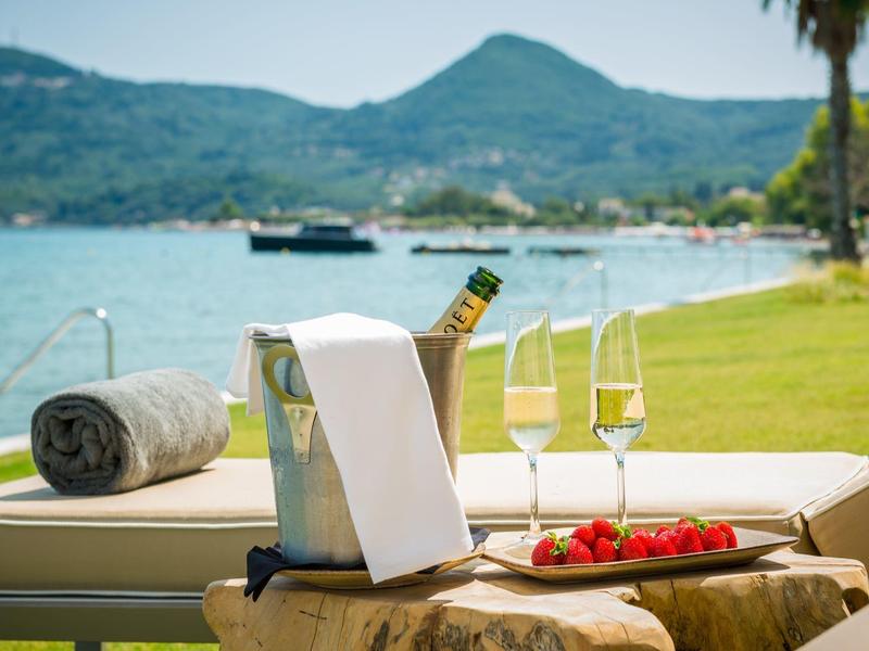 Liegematte mit Champagner, zwei Gläsern, Erdbeeren, Blick auf See und Berge im Hintergrund.