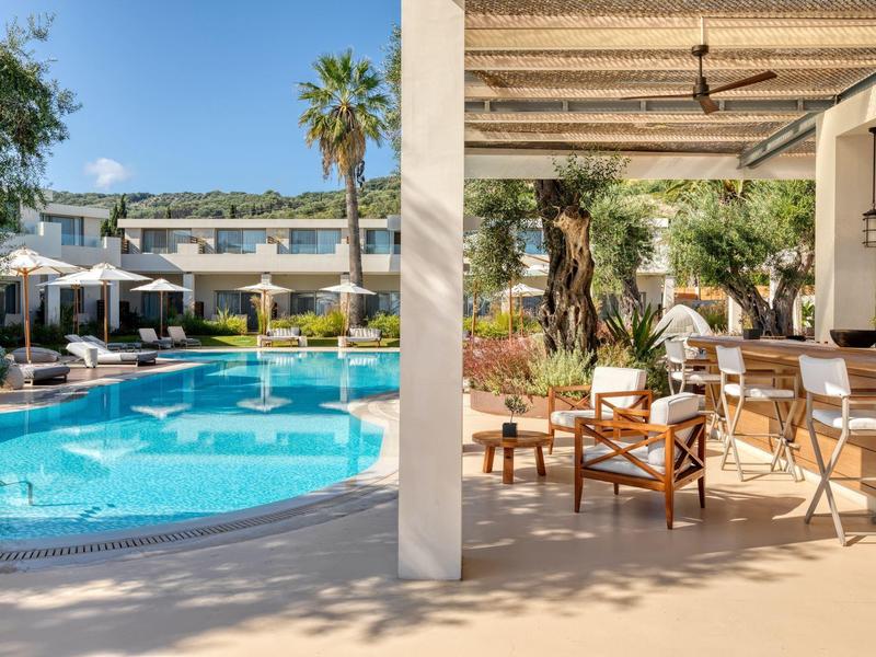 Moderner Poolbereich mit Liegestühlen, Sonnenschirmen und gemütlicher Sitzgruppe unter Pergola.