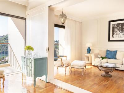 Helles Wohnzimmer mit Holzboden, weißen Wänden, blauen Akzenten und Balkon mit Ausblick.