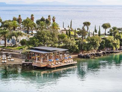 Kleine Insel mit vielen Bäumen und Palmen, Terrasse mit Stühlen über ruhigem Wasser.