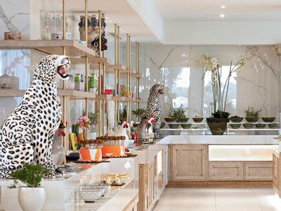 Helle Küche mit Holzschränken, großen Fenstern und Dalmatiner- sowie Gepardenfiguren auf der Arbeitsplatte.