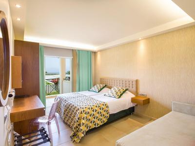 Helles Hotelzimmer mit Doppelbett, Schreibtisch, Stuhl und Balkon mit Ausblick.