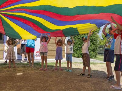 Kinder heben einen bunten Fallschirm im Freien während einer Gruppenaktivität.
