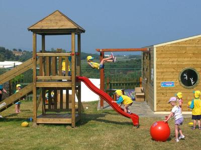 Ein Kinderspielplatz mit Holzgeräten und rutschenden Kindern im Hotel-Freizeitbereich.