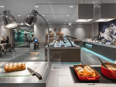 Moderne Hotellobby mit Buffet und Sitzbereichen, helle Beleuchtung und glänzende Oberflächen.