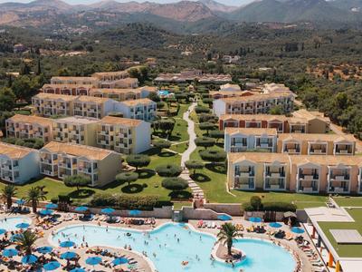 Hotelanlage mit Pool, Liegestühlen und gepflegten Gärten vor Berglandschaft.