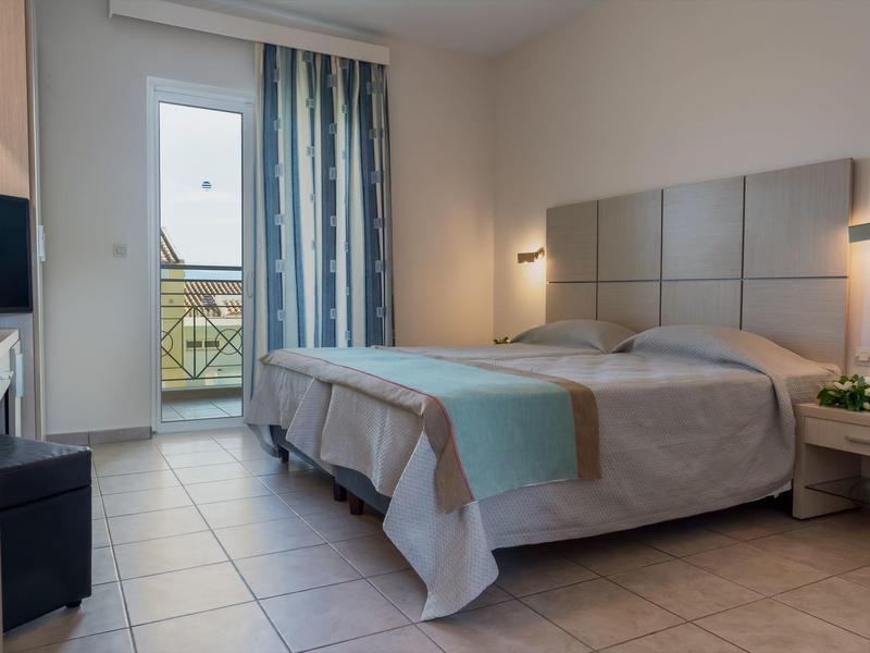 Modernes Schlafzimmer mit Doppelbett, grauer Bettdecke, blauem Vorhang und Balkonzugang.