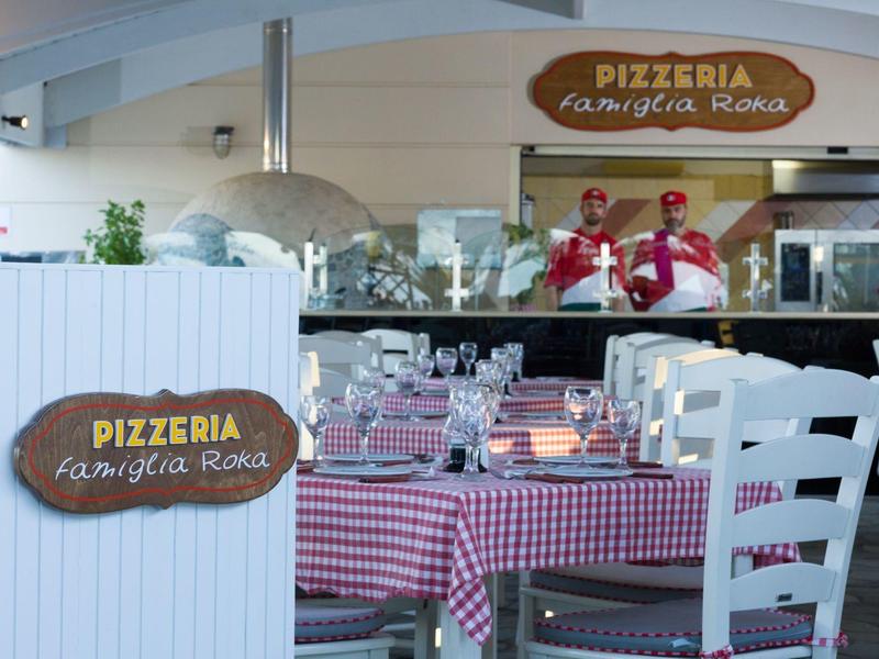 Gemütliche Pizzeria mit rot-weiß karierten Tischtüchern, Holztischen und wartendem Personal.