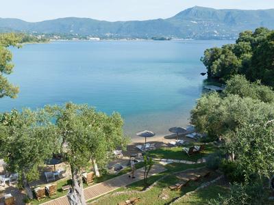 Vista de un lago con orilla arbolada y sombrillas en la ladera verde.