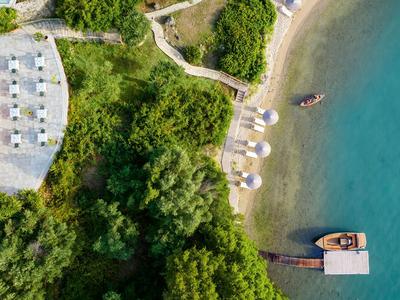 Vista aérea de una playa con sombrillas y un muelle sobre agua turquesa junto a vegetación verde.