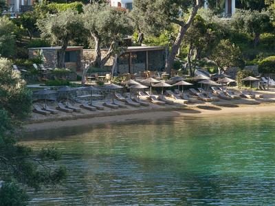 Entspannter Sandstrand mit Sonnenliegen und Sonnenschirmen vor klarem, grün-blauem Wasser.
