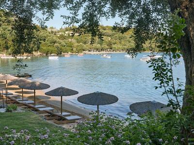 Blick auf einen See mit Sonnenschirmen am Ufer und Booten auf dem Wasser