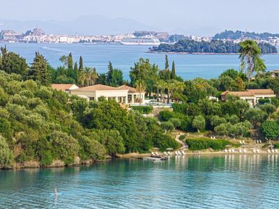 Blick auf eine Küstenlandschaft mit grüner Vegetation und Gebäuden am Wasser.