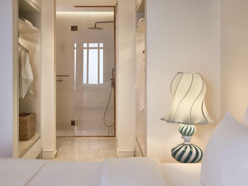 Blick auf ein modernes Badezimmer durch einen begehbaren Kleiderschrank mit sanfter Beleuchtung.