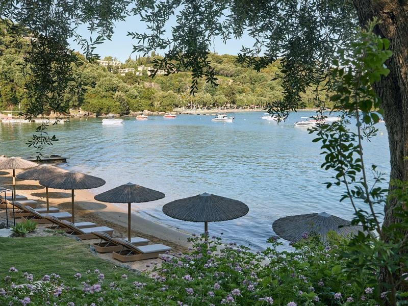 Blick auf einen See mit Sonnenschirmen am Ufer und Booten auf dem Wasser