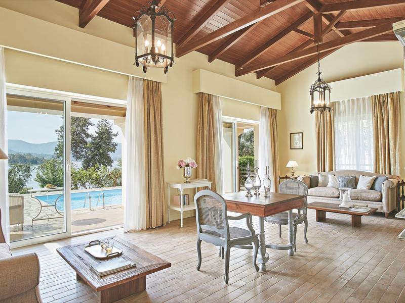 Helles Wohnzimmer mit Holzbalkendecke, eleganten Möbeln und Blick auf Pool und Meer.