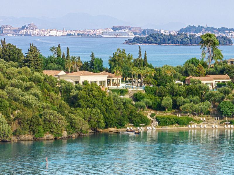 Blick auf eine Küstenlandschaft mit grüner Vegetation und Gebäuden am Wasser.