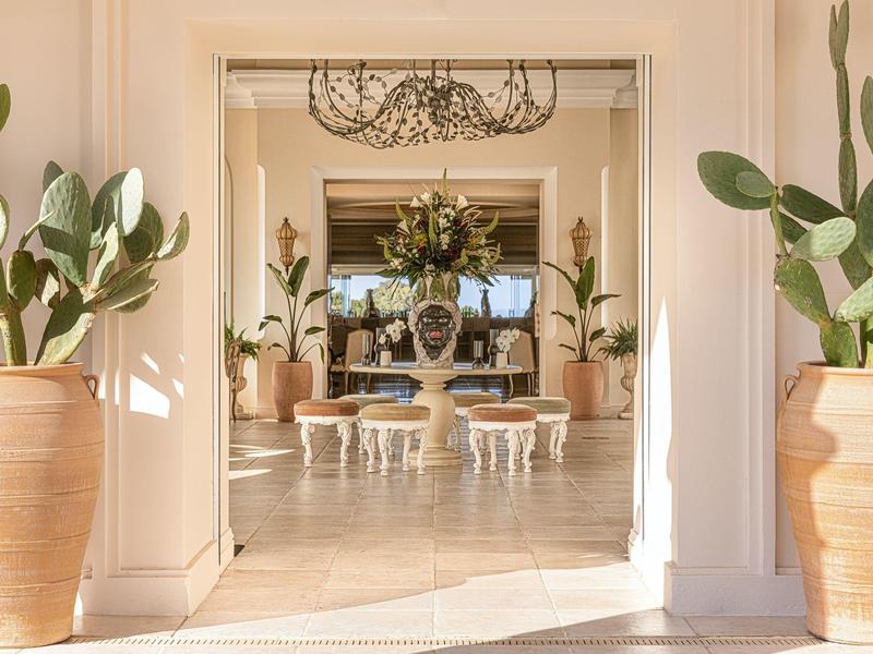 Heller Hotel-Lobbybereich mit Pflanzen in großen Töpfen und stilvoller Dekoration.