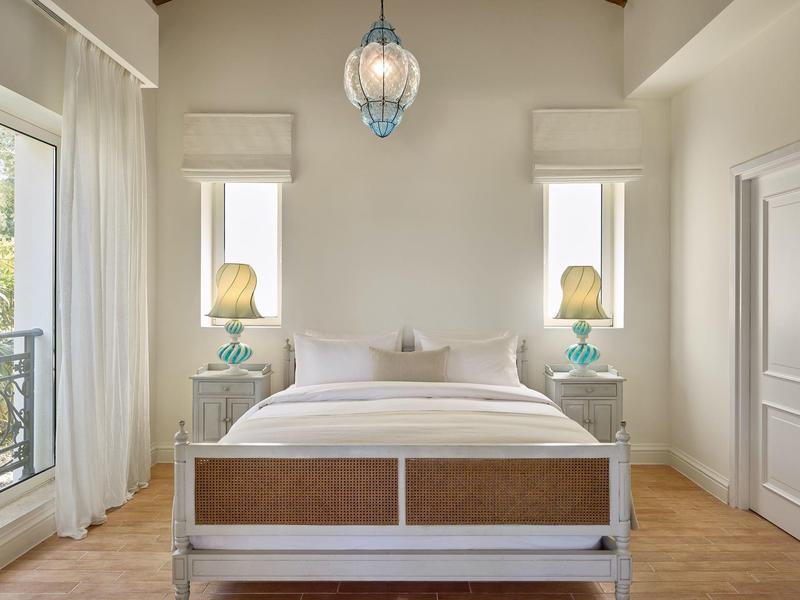 Helles Schlafzimmer mit Doppelbett, weißen Möbeln und dekorativen Lampen auf Nachttischen.