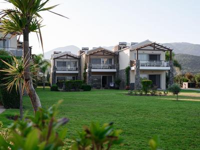 Drei moderne Ferienhäuser mit großen Fenstern und gepflegtem Rasen im Vordergrund