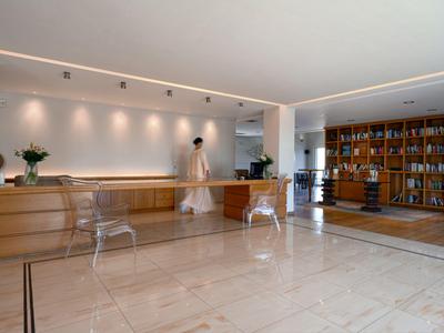 Moderne Hotellobby mit Rezeption, Holzverkleidung, Glastischen und Bücherregal