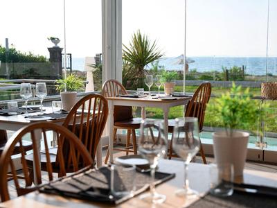 Hell eingerichtetes Restaurant mit Blick auf das Meer und einem gepflegten Garten.