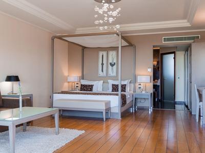 Helles Hotelzimmer mit Doppelbett, Holzboden, Sitzbereich und moderner Beleuchtung