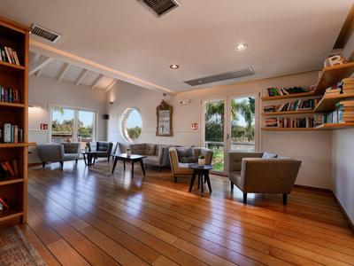 Moderner Hotel-Lounge-Bereich mit Holzboden, bequemen Sitzmöbeln und Bücherregalen.
