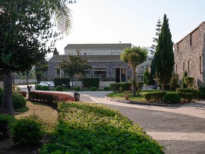 Ein gepflegter Hotelgarten mit Wegen, Büschen und Bäumen vor einem Gebäude aus Stein.