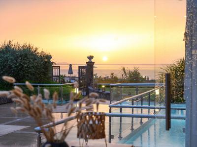 Sonnenuntergang über einem Pool mit Sitzbereich und Meerblick