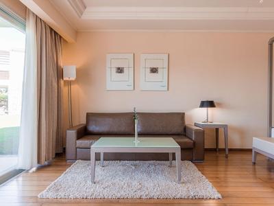 Modernes Wohnzimmer mit braunem Sofa, grauem Teppich und großem Fenster mit Blick nach draußen.