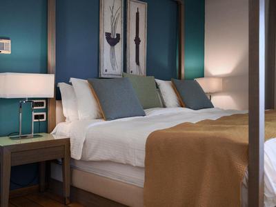 Modern eingerichtetes Hotelzimmer mit großem Bett, Nachttischen und warmem Licht.