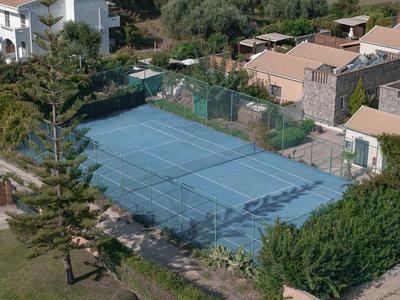 Blick auf einen blauen Tennisplatz mit angrenzenden Gebäuden und Bäumen