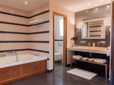 Modernes Badezimmer mit Badewanne, Waschtisch und Spiegel, in warmen Farbtönen gestaltet.