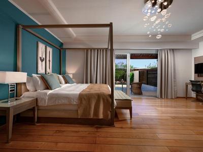 Elegantes Hotelzimmer mit Himmelbett, Holzboden und Zugang zu Terrasse mit Blick auf den Garten.