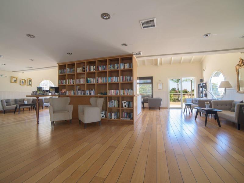 Heller Hotel-Lobbybereich mit Holzfußboden, Bücherregal und modernen Sitzgelegenheiten.