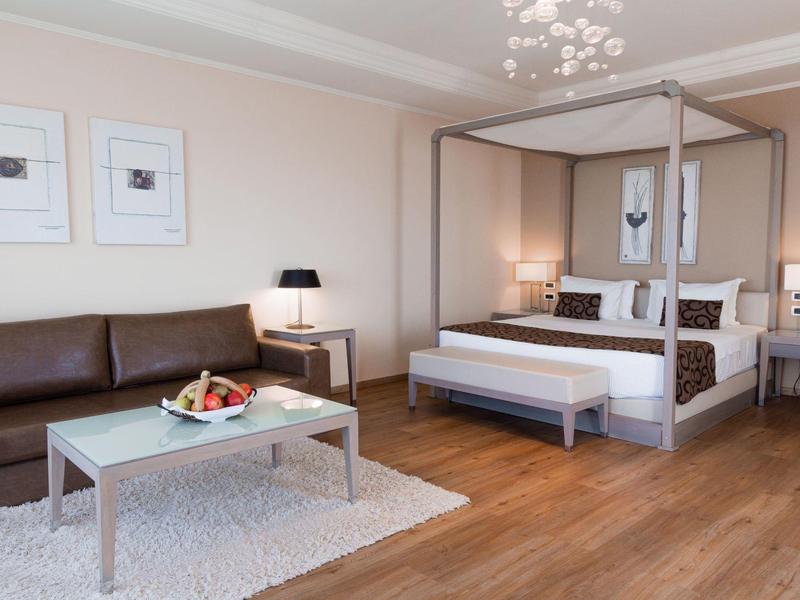 Modern eingerichtetes Hotelzimmer mit Himmelbett, Sofa, Couchtisch und Holzboden.