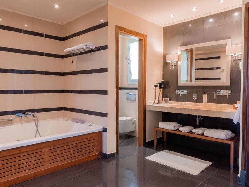 Modernes Badezimmer mit Badewanne, Waschtisch und Spiegel, in warmen Farbtönen gestaltet.