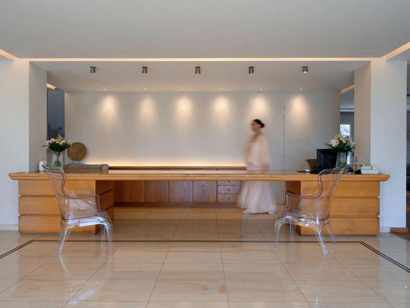 Eleganter Hotellobby-Empfangstresen mit zwei Stühlen und Person in Bademantel.