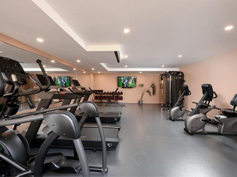 Moderner Fitnessraum mit Laufbändern, Fahrrädern und Gewichten in einem Hotel.